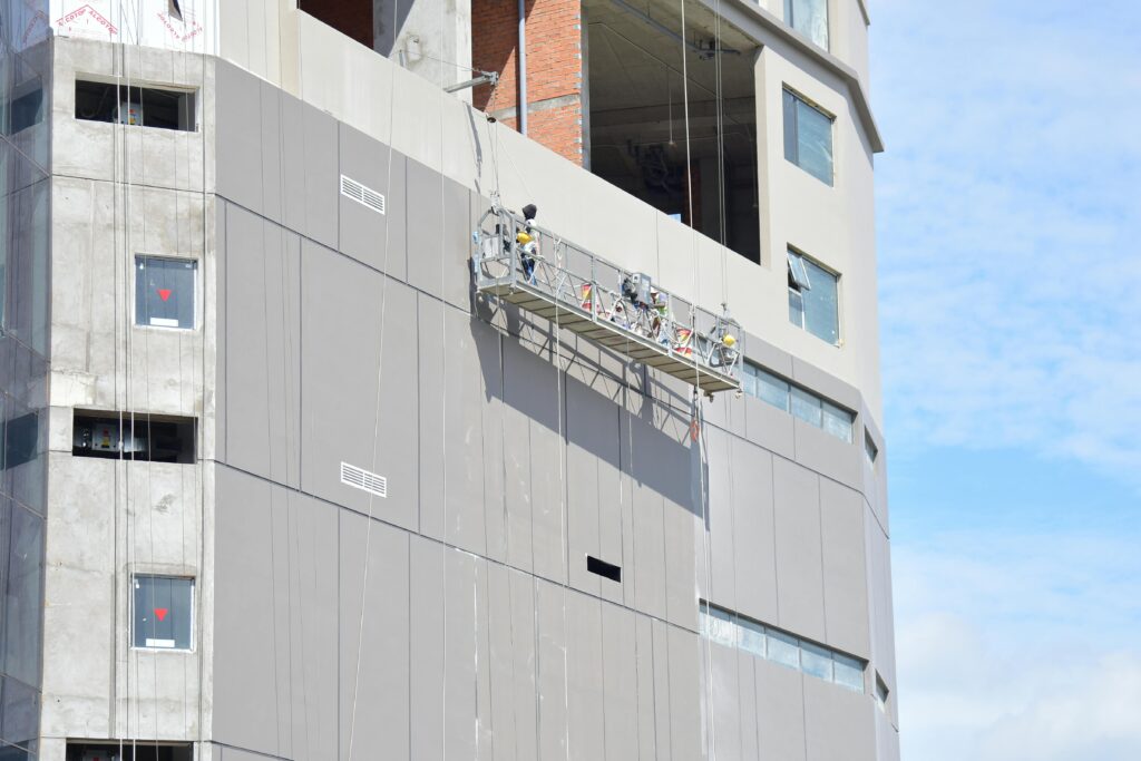 pexels photo 34297398 34297398 Workers on a suspended platform conducting maintenance on a high-rise building facade.